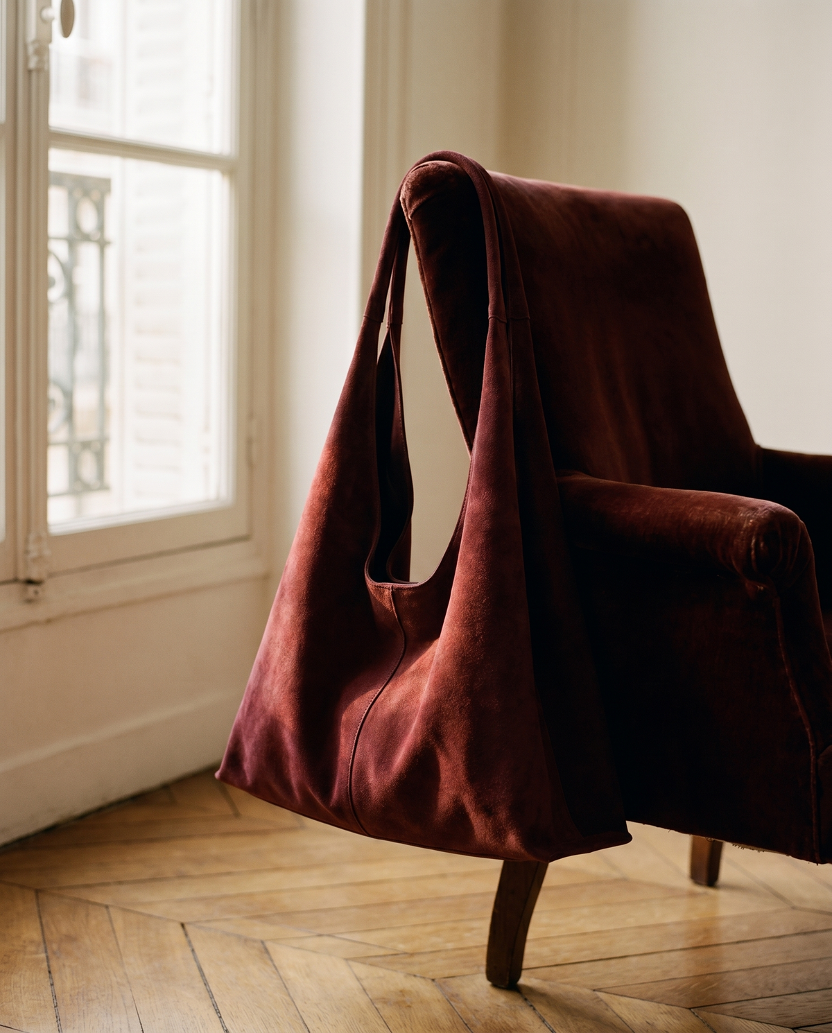 Nomade Bordeaux suede tote on velvet armchair